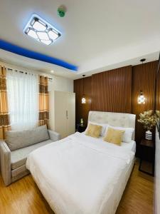 een slaapkamer met een groot wit bed en een bank bij Lou- Mesaverte Residences in Cagayan de Oro
