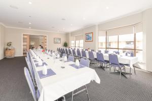 a banquet hall with white tables and blue chairs at Seasonal South Motel & Function Centre in Ulverstone