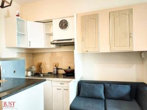 a kitchen with white cabinets and a clock on the wall at King Size Bed At the Heart Of the City in Cagayan de Oro +7 photos
