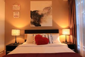 a red heart pillow on a bed with two lamps at Suasana Bukit Ceylon Residence in Kuala Lumpur