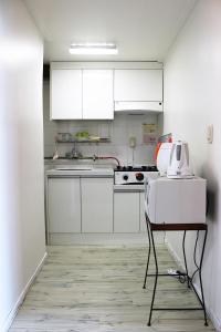 - une cuisine avec des placards blancs et une table avec un grille-pain dans l'établissement Dreaming Forest Pension Seogwipo, à Seogwipo