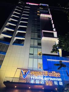 een hoog gebouw met een bord ervoor bij V V Hotel Battambang in Battambang