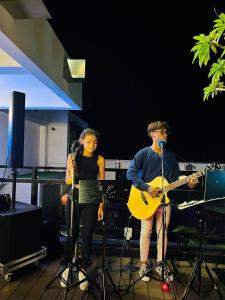 Um homem e uma mulher cantam e tocam guitarras. em V V Hotel Battambang em Battambang