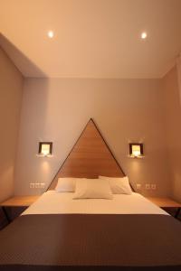 een slaapkamer met een bed met een driehoekig hoofdeinde bij Hôtel Amirauté in Toulon