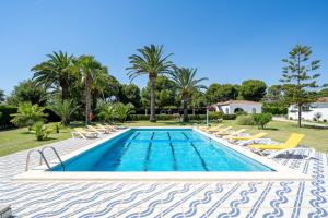 a swimming pool with chaise lounge chairs and trees at Complejo Colibri 8 in Cambrils