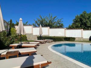 una piscina con bancos y sombrillas junto a una piscina en Villa Mia en Sozopol