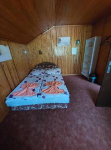 ein Schlafzimmer mit einem Bett in einem Holzzimmer in der Unterkunft Garden Etterem Kávézó és Panzió Tahitótfalú in Tahitótfalu