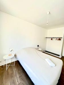 een witte slaapkamer met een groot bed en 2 tafels bij Capucins - Très bel appartement hyper centre in Reims