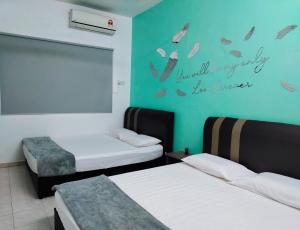 een kamer met 2 bedden en een muur met een bord bij U&I HOMESTAY KAMPAR in Kampar