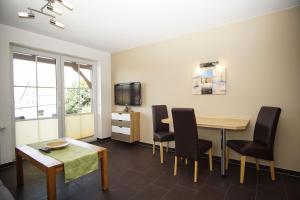 ein Wohnzimmer mit Tisch und Stühlen und einem Fernseher in der Unterkunft Schicke FeWo mit Terrasse, gratis Nutzung vom AHOI Erlebnisbad und Sauna in Sellin - Haus De niege Wech FeWo 01 in Thiessow