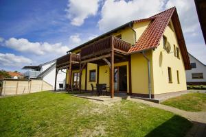 ein gelbes Haus mit einem roten Dach in der Unterkunft Schicke FeWo mit Terrasse, gratis Nutzung vom AHOI Erlebnisbad und Sauna in Sellin - Haus De niege Wech FeWo 01 in Thiessow