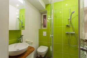 een groene en witte badkamer met een wastafel en een douche bij Appartement entièrement rénové proche des commerces in Biarritz