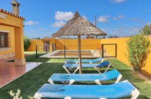 two lounge chairs and an umbrella in a yard at Casa Calas Boliña in Roche