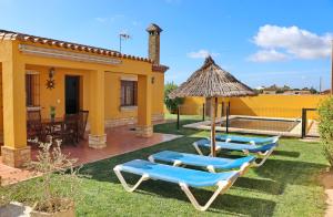 a group of chairs and an umbrella and a house at Casa Calas Boliña in Roche