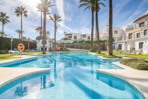a swimming pool with palm trees and a building at Marina Real 2391 in Manilva