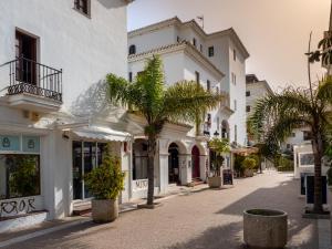 a street with white buildings and palm trees at Marina Real 2391 in Manilva