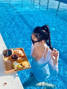 uma mulher sentada numa piscina com uma bandeja de comida em Merry Land Hotel Da Nang em Da Nang