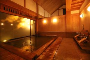 ein großer Pool mit Wasser in einem Zimmer mit Holzwänden in der Unterkunft 野沢温泉　奈良屋旅館 in Nozawa Onsen