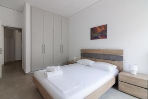 a white bedroom with a large white bed and cabinets at Renovated Apartment next to Panathenaic Stadium in Athens