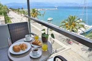 a table with two plates of food on a balcony with the ocean at Agamemnon Hotel in Nafplio