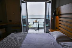 a bedroom with a bed and a balcony with a table at Agamemnon Hotel in Nafplio