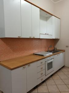uma cozinha com armários brancos e um lavatório em Villa Roccia Scura dell'Etna em Zafferana Etnea