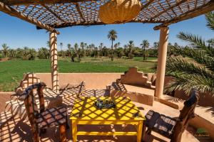 einen gelben Tisch und Stühle auf einer Terrasse in der Unterkunft Ecolodge La Palmeraie in Ouarzazate