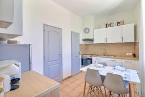 - une cuisine avec des placards blancs, une table et des chaises dans l'établissement LE REGORDANE - Appartement 4 personnes - Centre WiFi Cosy, à Saint-Gilles