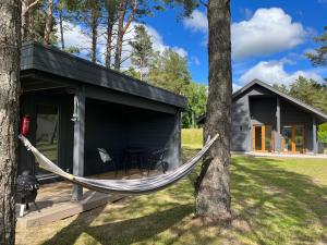 a hammock in front of a black cabin at Villa Männituka Suvetuba in Kirikuküla