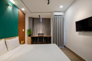 Un dormitorio con cama, escritorio y televisión. en LÁ HOTEL RIVERSIDE, en Ho Chi Minh