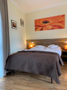 a bedroom with a large bed with a large flower painting on the wall at Willa Słoneczna in Okuninka