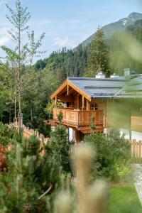 uma cabana de madeira na floresta com montanhas ao fundo em Natursinn Mountainchalets em Flachau