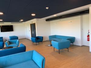 une salle d'attente avec des chaises bleues et une télévision à écran plat dans l'établissement CIS Lamourelle Centre International de Sejour, à Carcassonne