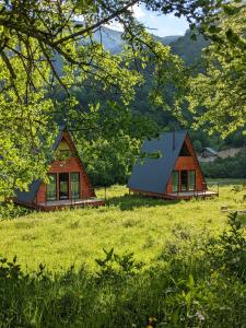 two houses in a field with grass and trees at Labna Huts in Mestia