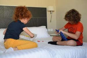 two children sitting on a bed playing with legos at Hôtel Amirauté in Toulon