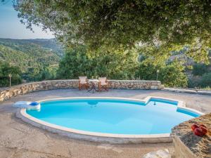 a pool with two chairs and a table next to it at Stone Built Private villa Limeri with pool, BBQ & Shaded Patio in Áno Valsamóneron