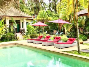 a group of red chairs and umbrellas next to a pool at Carpe Diem Residence in Thongsala