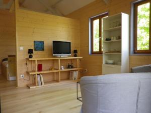 uma sala de estar com uma televisão numa parede de madeira em maison sur pilotis em Cazals