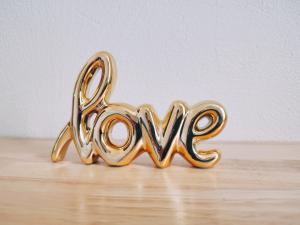 a gold sign spelling the word love sitting on a wooden floor at LE REGORDANE - Appartement 4 personnes - Centre WiFi Cosy in Saint-Gilles