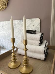 due candele su un tavolo di fronte a una pila di asciugamani di La Vigie, Spa a Spa