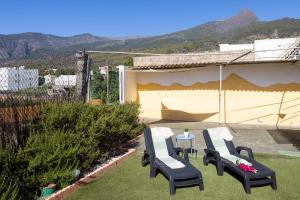 a patio with two chairs and a table on the grass at Home2Book La Cruz de Arafo, BBQ & Terrace in Arafo
