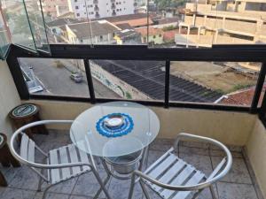 uma mesa e cadeiras numa varanda com uma janela em Apartamento aconchegante a 100m da praia na Praia Grande