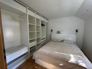 a white bedroom with a bed and shelves at Pod Galetovcem in Bohinjska Bela