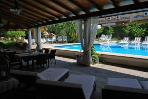 a patio with a table and chairs next to a pool at B&B Il Resort Dell'Artista in Venetico