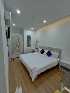 1 dormitorio con 1 cama blanca grande con almohadas azules en Onhotel Nice Buôn Ma Thuột, en Buon Ma Thuot