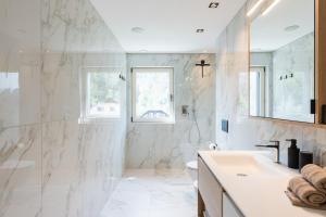 a white bathroom with a sink and a toilet at VANEA - Alp Relax Guesthouse in Chienes +112 photos