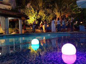 a group of people standing next to a swimming pool with lit up balloons at B&B Il Resort Dell'Artista in Venetico