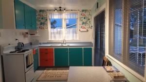 a kitchen with green cabinets and a sink and a window at Beach Belle in Bowentown