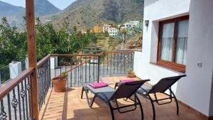 a balcony with two chairs and a table with a view at Casa La Sabina Roja 1 - Casa con impresionantes vistas sobre Hermigua y el mar in Hermigua