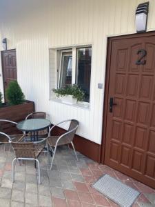 a patio with a table and chairs next to a door at Pokoje blisko morza in Sarbinowo